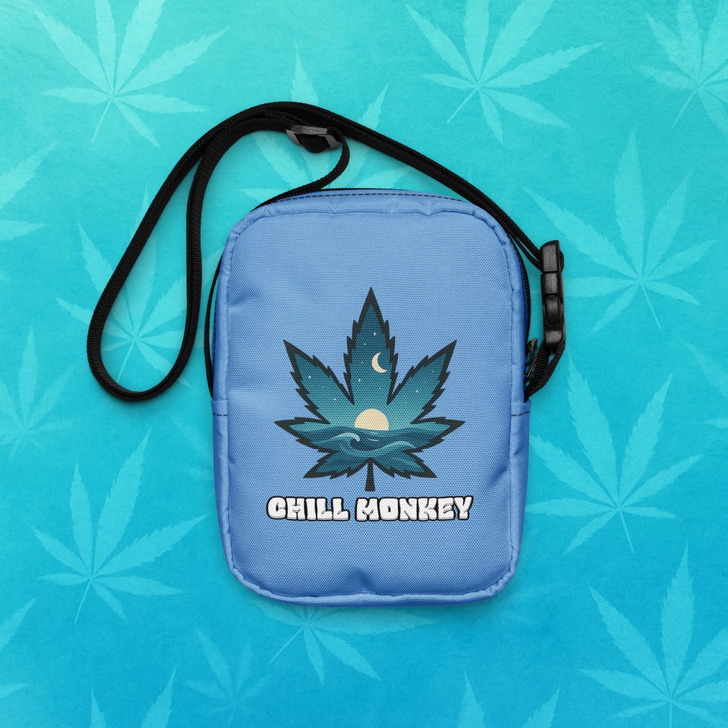 Small blue cross-body utility bag with black adjustable strap, featuring a stylized cannabis leaf filled with ocean waves, moon and sun graphic above the text “Chill Monkey”; front view on aqua leaf backdrop.
