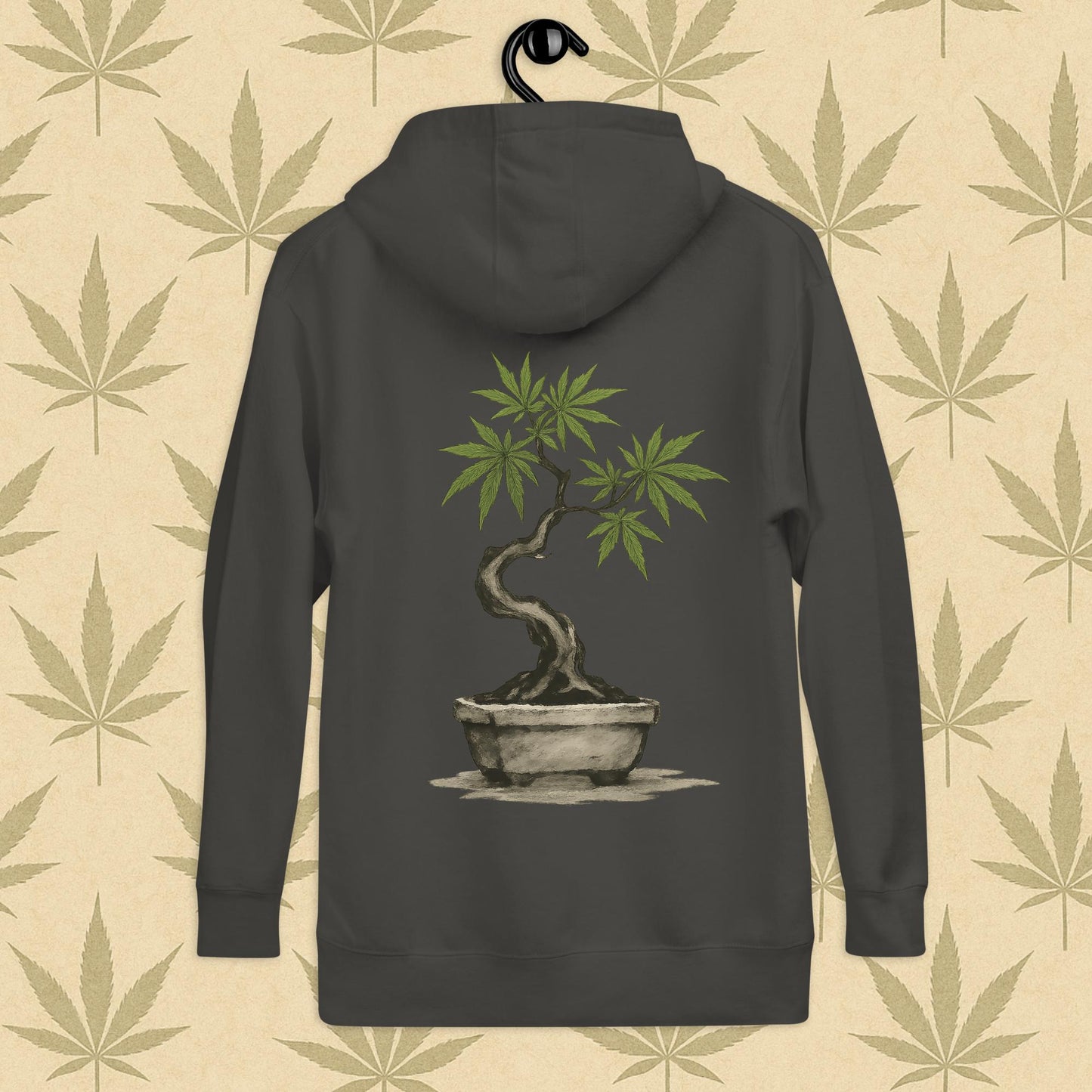 Back view of a grey-colored unisex premium hoodie featuring a large Japanese sumi-e style cannabis-bonsai illustration centered on the garment against a neutral leaf backdrop.