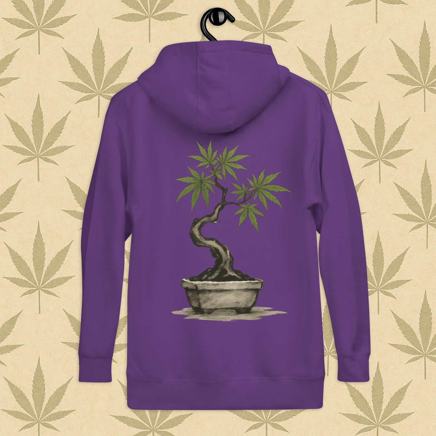 Back view of a purple-colored unisex premium hoodie featuring a large Japanese sumi-e style cannabis-bonsai illustration centered on the garment against a neutral leaf backdrop.