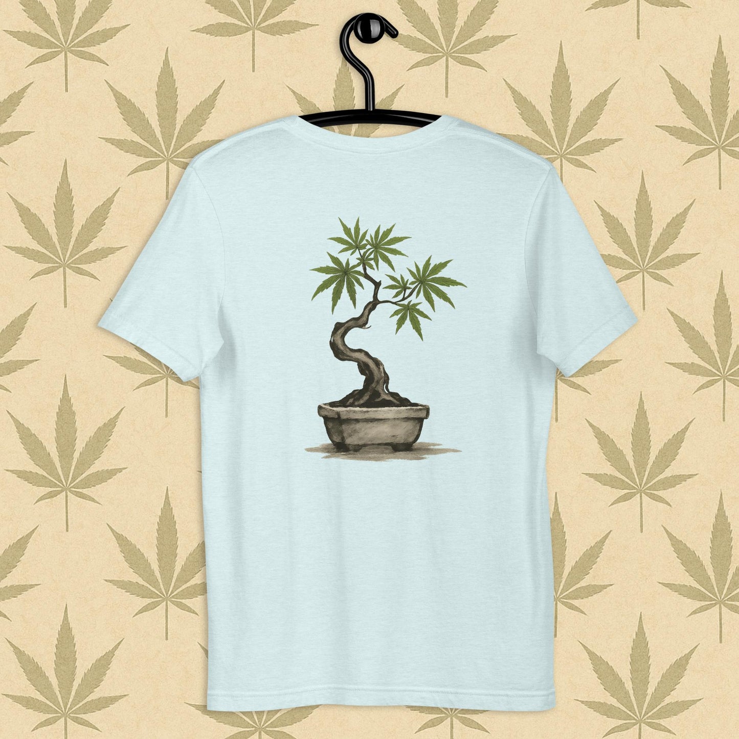 Back view of a blue unisex Bella+Canvas tee showcasing a large hand-painted cannabis-bonsai illustration in Japanese sumi-e style, centered on the shirt against a neutral leaf backdrop.