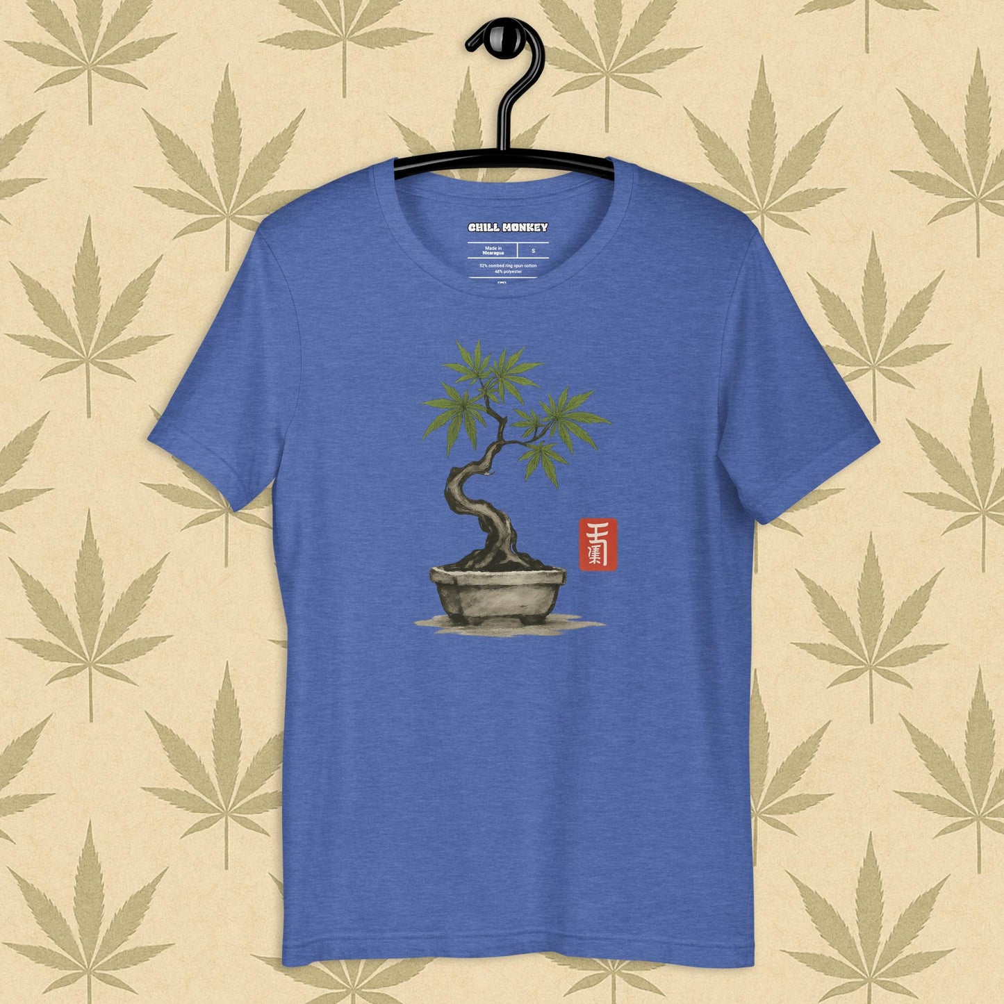 Front view of a blue unisex Bella+Canvas tee featuring a hand-drawn cannabis-bonsai pot with Japanese-style brushwork and a small red hanko seal, shown on a neutral leaf backdrop.