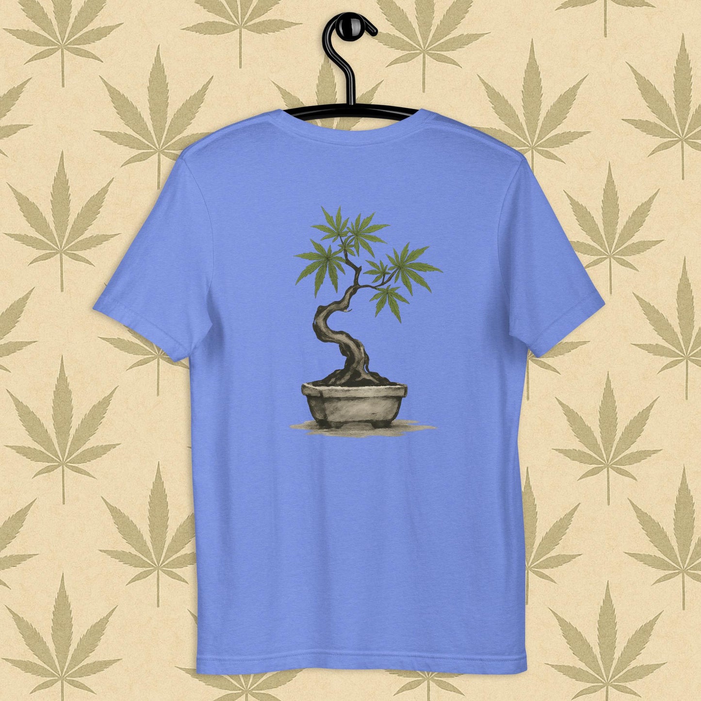 Back view of a blue unisex Bella+Canvas tee showcasing a large hand-painted cannabis-bonsai illustration in Japanese sumi-e style, centered on the shirt against a neutral leaf backdrop.