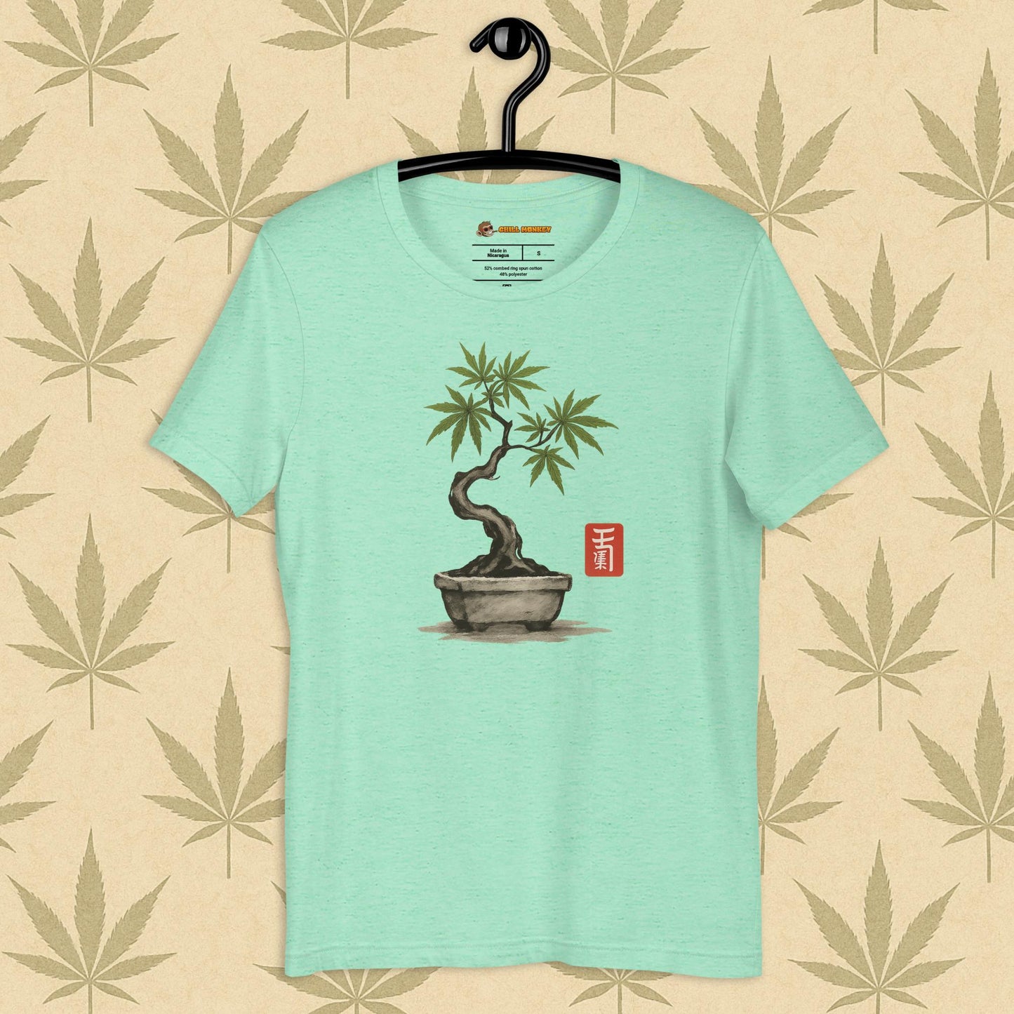 Front view of a mint unisex Bella+Canvas tee featuring a hand-drawn cannabis-bonsai pot with Japanese-style brushwork and a small red hanko seal, shown on a neutral leaf backdrop.