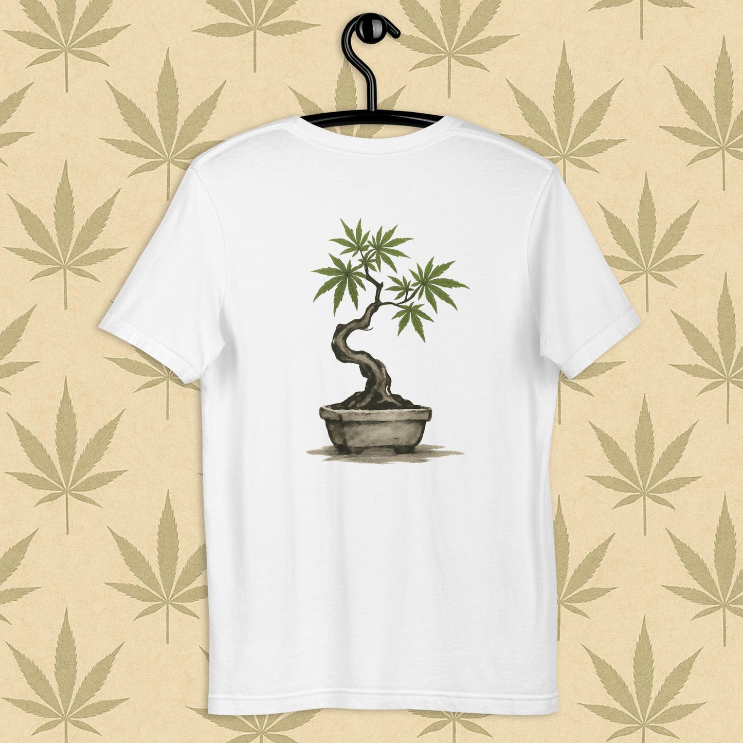 Back view of a white unisex Bella+Canvas tee showcasing a large hand-painted cannabis-bonsai illustration in Japanese sumi-e style, centered on the shirt against a neutral leaf backdrop.