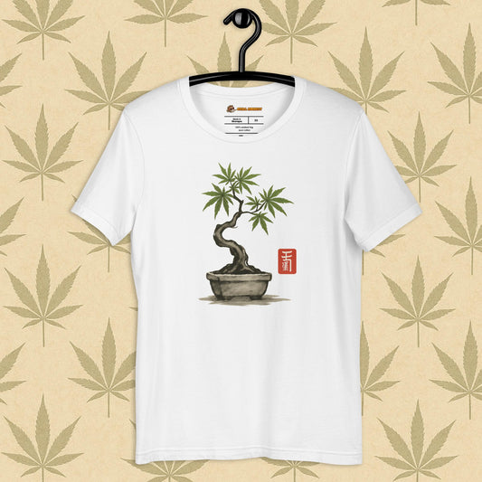 Front view of a white unisex Bella+Canvas tee featuring a hand-drawn cannabis-bonsai pot with Japanese-style brushwork and a small red hanko seal, shown on a neutral leaf backdrop.