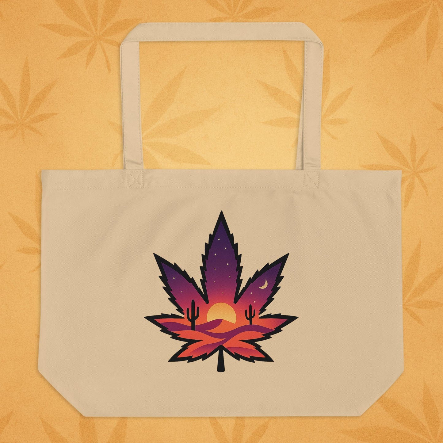 Large oyster-tone eco tote bag with a bold, purple-to-orange desert-sunset cannabis leaf graphic on the front, shown against a sandy boho backdrop (front view).