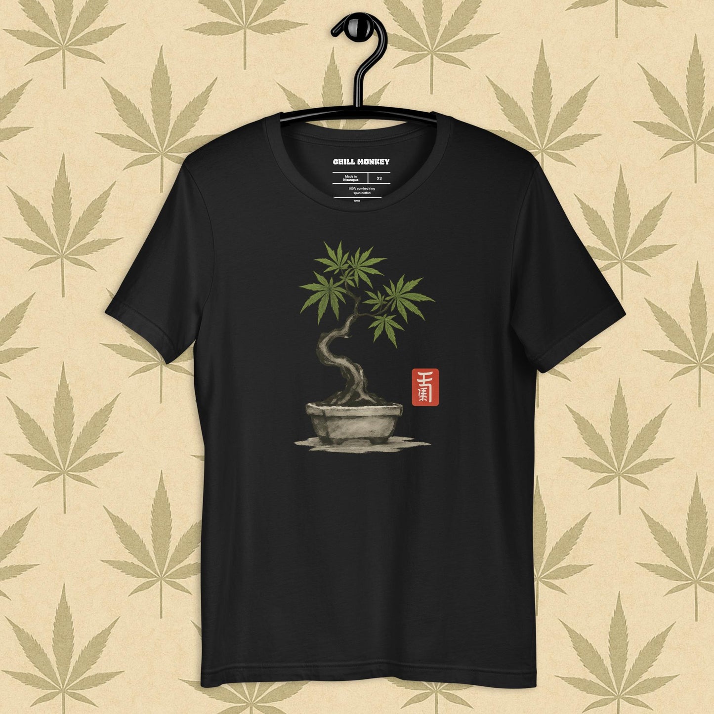Front view of a vintage black unisex Bella+Canvas tee featuring a hand-drawn cannabis-bonsai pot with Japanese-style brushwork and a small red hanko seal, shown on a neutral leaf backdrop.