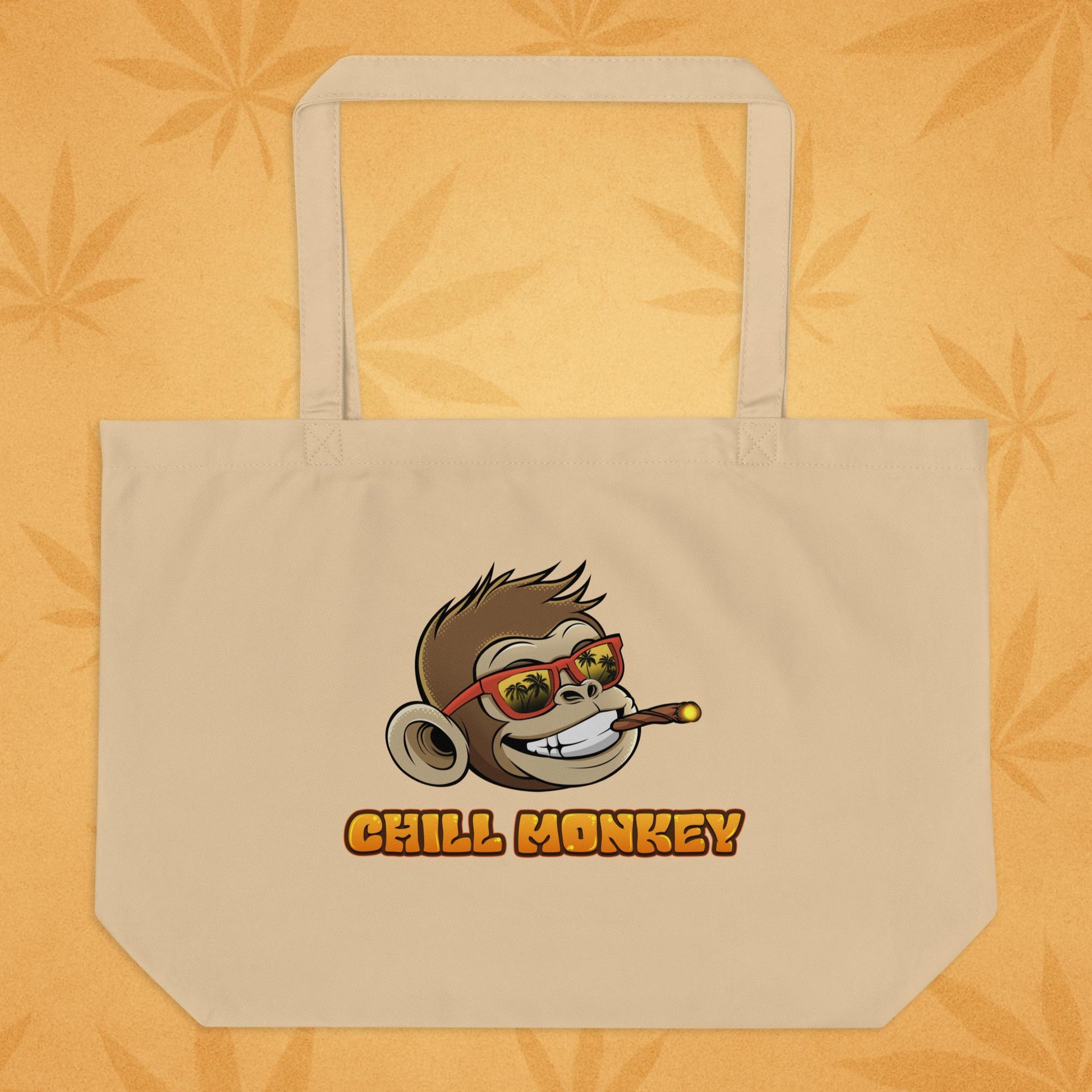 Back view of the same oyster-sand eco tote featuring the smiling Chill Monkey head in red sunglasses and the text “CHILL MONKEY,” displayed on a warm desert-leaf backdrop
